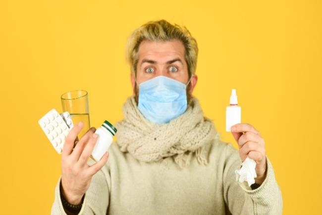 גבר עם מסכה, מחזיק בידיו תוספי תזונה כדרך להגנה על המערכת החיסונית בחורף